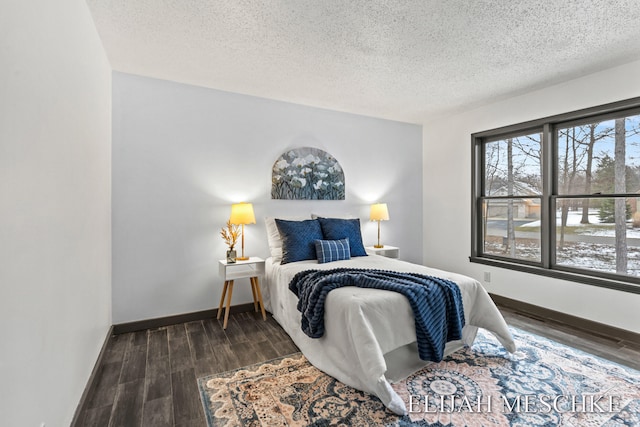 bedroom with a textured ceiling, wood finished floors, and baseboards