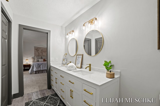 full bath featuring wood finished floors, a textured ceiling, connected bathroom, and vanity