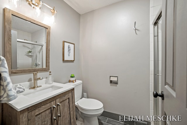full bathroom with tiled shower, toilet, and vanity