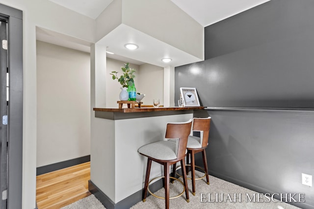 bar with baseboards, a bar, and carpet