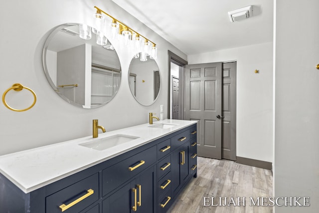 bathroom featuring double vanity, a sink, wood finished floors, and visible vents