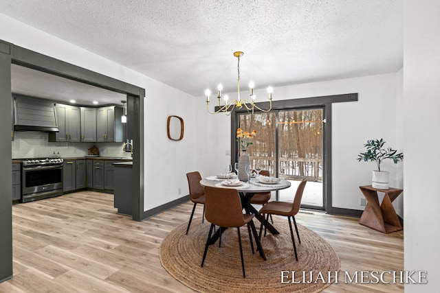 dining space with a textured ceiling, light wood-style floors, a chandelier, and baseboards