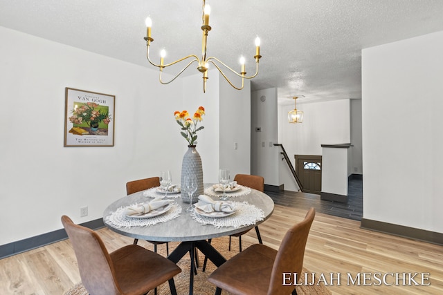 dining space featuring an inviting chandelier, a textured ceiling, wood finished floors, and baseboards