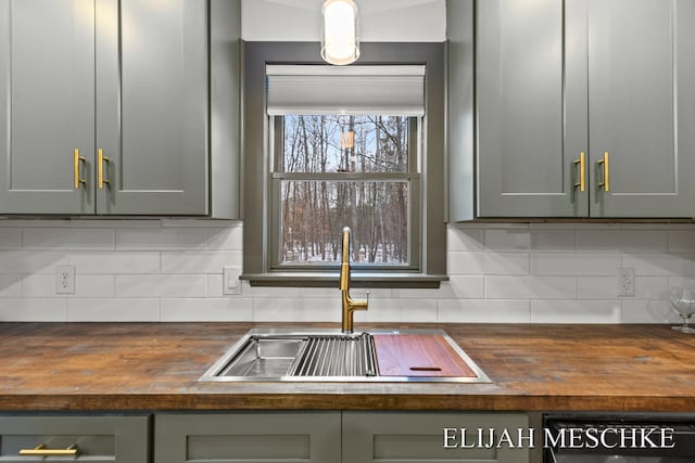 interior details featuring tasteful backsplash, butcher block countertops, dishwasher, and a sink