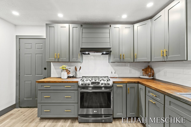 kitchen with wood counters, tasteful backsplash, light wood finished floors, and stainless steel range with gas stovetop