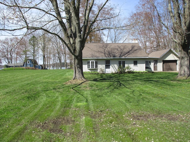view of front of home with a chimney, a front yard, a shingled roof, and a garage