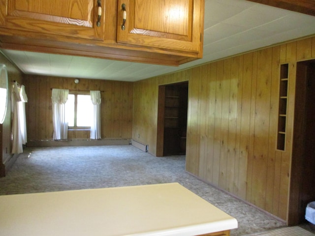 unfurnished room featuring wood walls, carpet, and a baseboard radiator