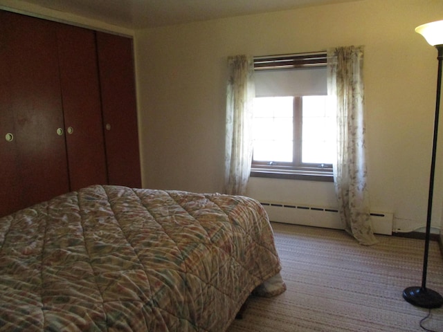 bedroom featuring a baseboard radiator, carpet flooring, and a closet
