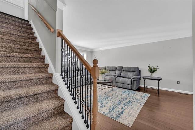 stairway featuring baseboards, ornamental molding, wood finished floors, and visible vents