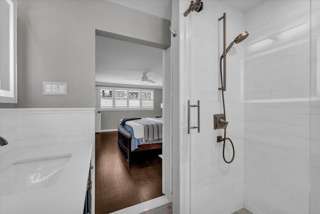 bathroom with wood finished floors, a sink, a ceiling fan, and a stall shower