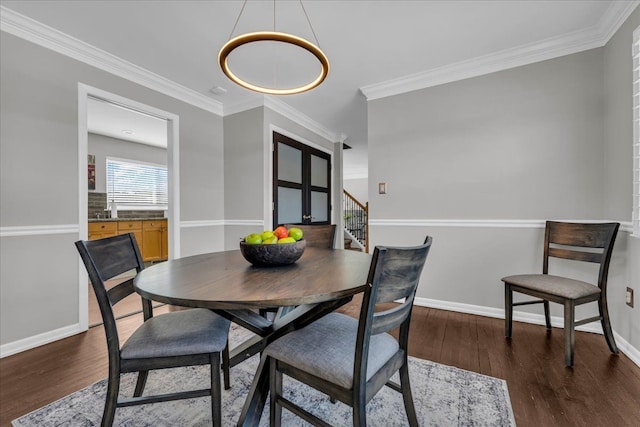 dining area with dark wood-type flooring, ornamental molding, and baseboards