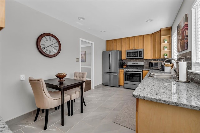 kitchen with tasteful backsplash, open shelves, a sink, light stone counters, and stainless steel appliances