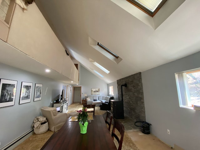 dining space featuring a skylight, a baseboard radiator, carpet flooring, a wood stove, and high vaulted ceiling