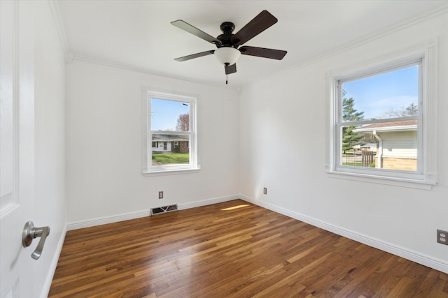 spare room featuring baseboards, visible vents, wood finished floors, and crown molding