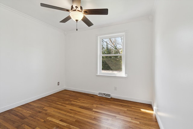 spare room with ceiling fan, crown molding, visible vents, baseboards, and wood finished floors