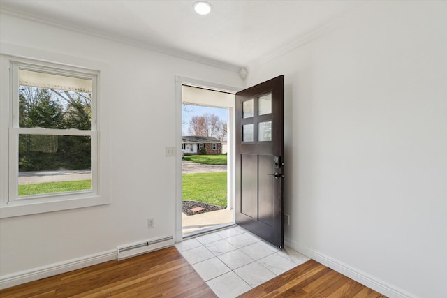 foyer with a baseboard heating unit, ornamental molding, light wood finished floors, baseboards, and visible vents