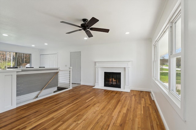 unfurnished living room with recessed lighting, wood finished floors, a brick fireplace, baseboards, and a ceiling fan