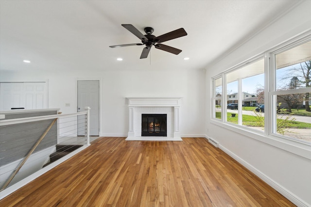 unfurnished living room featuring baseboards, recessed lighting, wood finished floors, and a brick fireplace