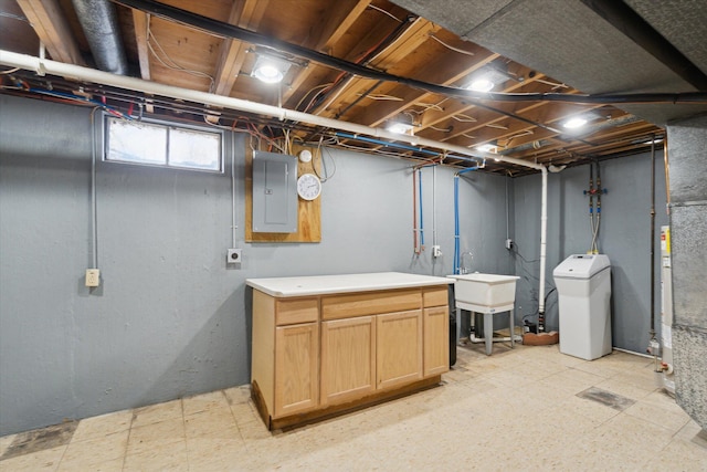 basement featuring a sink, electric panel, and light floors