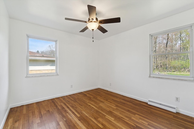 spare room with a baseboard radiator, a wealth of natural light, hardwood / wood-style floors, and a ceiling fan