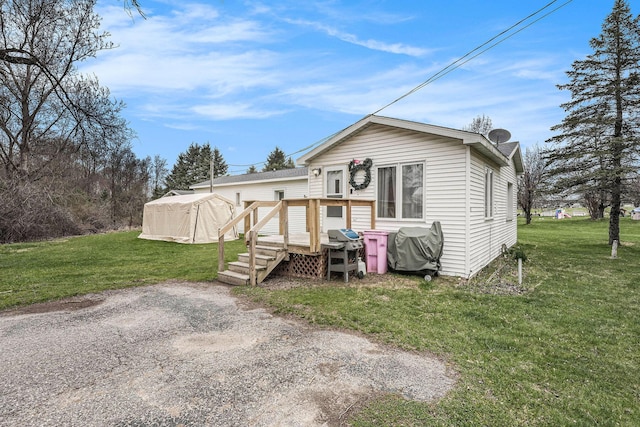rear view of property featuring a lawn and a deck