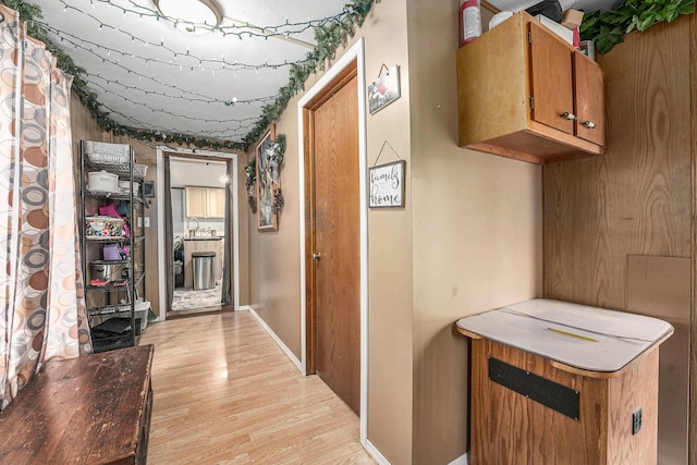 corridor featuring a sink, baseboards, and light wood-style floors