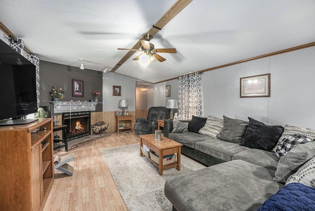 living area featuring a lit fireplace, a ceiling fan, wood finished floors, and lofted ceiling