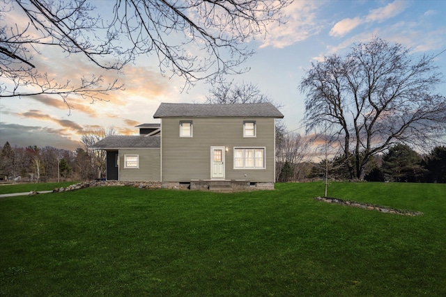 back of property at dusk with a yard