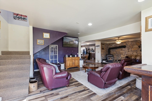 living area with stairs, recessed lighting, wood finished floors, and a wood stove