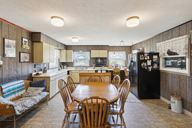 dining area featuring baseboards, wood walls, and a textured ceiling