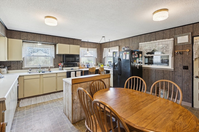 kitchen with light countertops, a textured ceiling, a sink, and black appliances