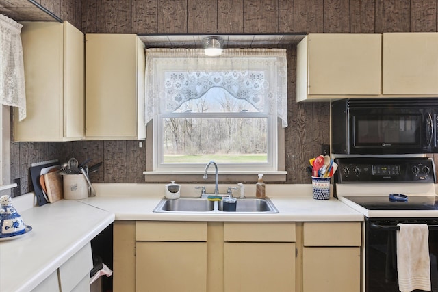 kitchen featuring a sink, black appliances, cream cabinets, and light countertops