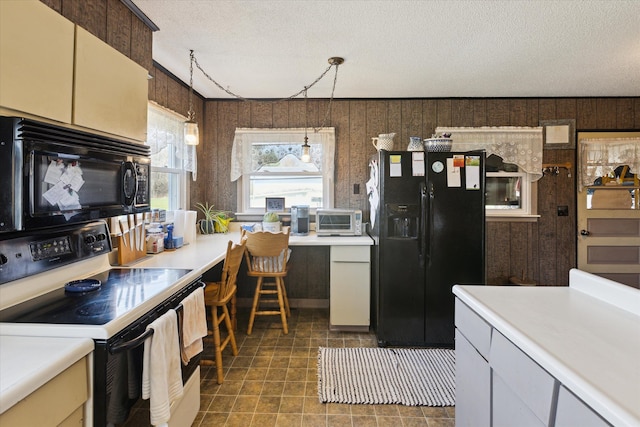 kitchen with a textured ceiling, pendant lighting, light countertops, a toaster, and black appliances
