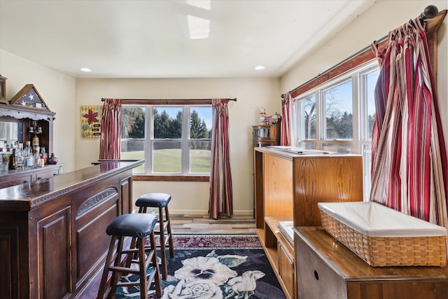 interior space featuring baseboards, a bar, recessed lighting, and dark wood-type flooring