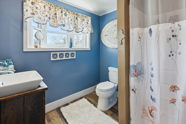 full bath featuring wood finished floors, baseboards, vanity, toilet, and ornamental molding