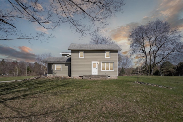rear view of property featuring a lawn, a shingled roof, and entry steps