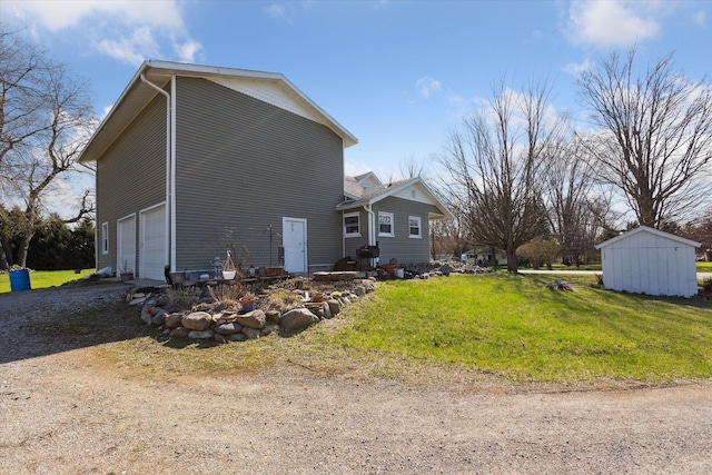 view of side of property with dirt driveway, a lawn, and a garage