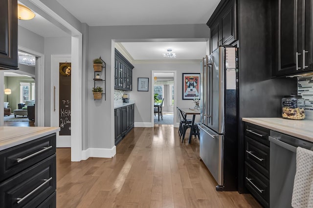 kitchen featuring wood finished floors, appliances with stainless steel finishes, light countertops, and dark cabinetry