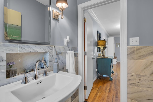 bathroom featuring ornamental molding, tile walls, a sink, and wood finished floors