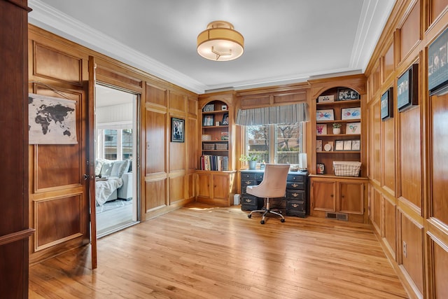 office with crown molding, wood walls, visible vents, light wood finished floors, and built in shelves