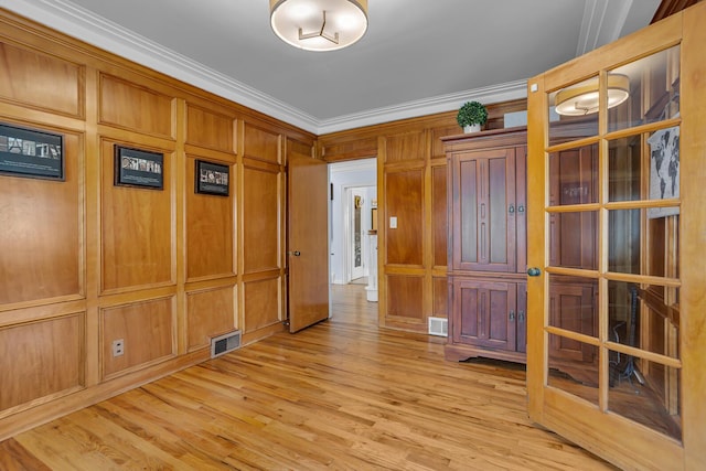 unfurnished room with crown molding, visible vents, and light wood-style floors