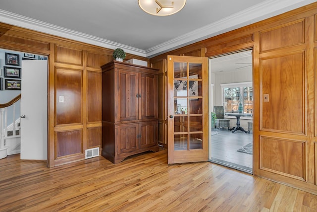 interior space featuring visible vents, light wood-type flooring, crown molding, and stairs