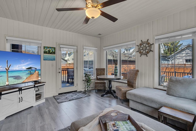 sunroom featuring wood finished floors, a wooden deck, and plenty of natural light