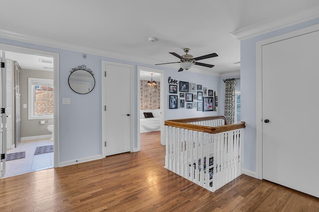 hallway with crown molding, wood finished floors, and baseboards