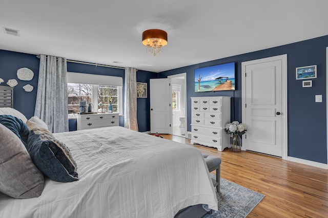 bedroom with visible vents, wood finished floors, and baseboards