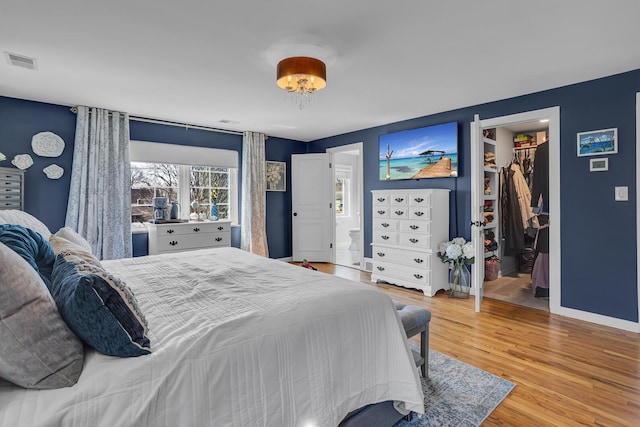 bedroom featuring visible vents, baseboards, a closet, wood finished floors, and a spacious closet