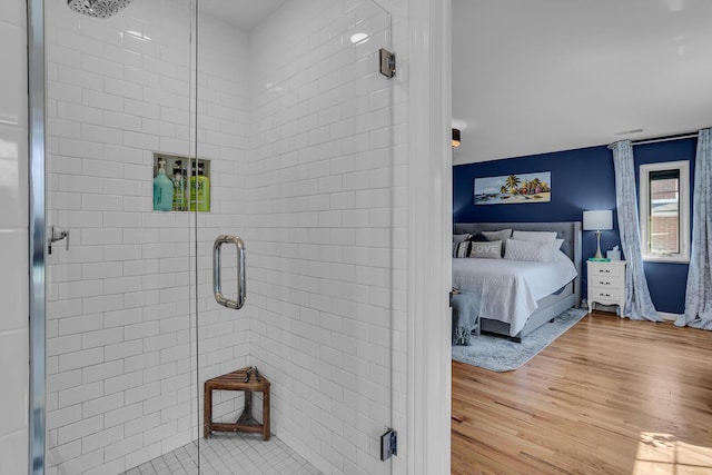 bathroom featuring wood finished floors, a stall shower, and ensuite bathroom