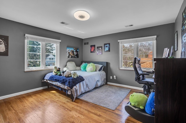 bedroom with wood finished floors, visible vents, and baseboards