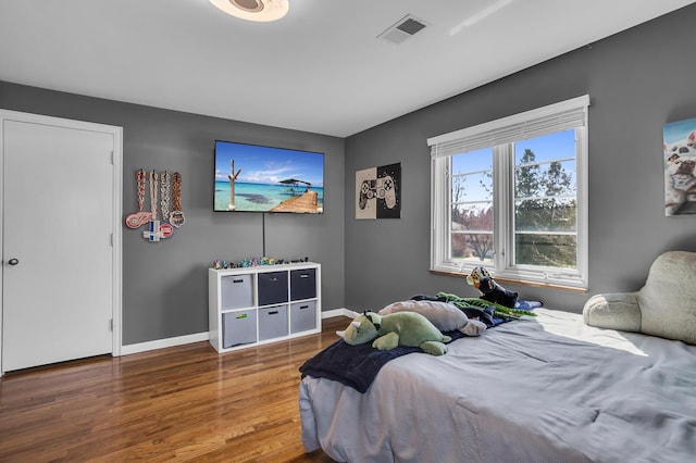 bedroom with visible vents, wood finished floors, and baseboards