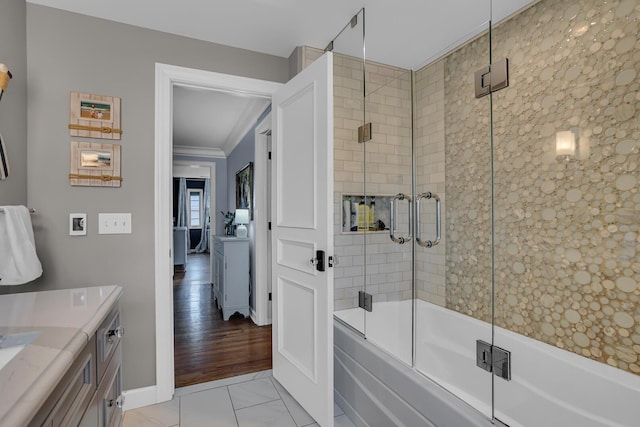 bathroom featuring combined bath / shower with glass door, baseboards, crown molding, and vanity